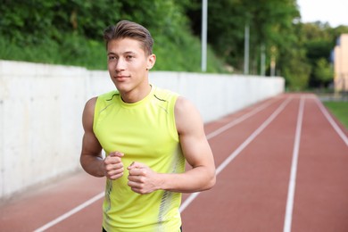 Photo of Sporty man running at stadium, space for text. Healthy lifestyle