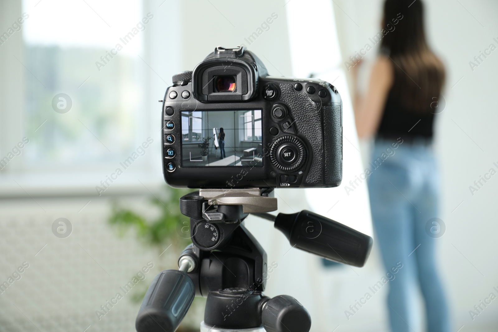 Photo of Woman near mirror in studio, focus on video camera recording her