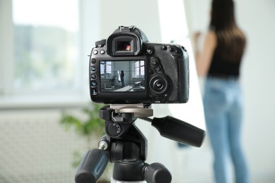 Photo of Woman near mirror in studio, focus on video camera recording her