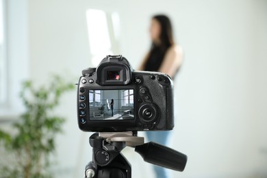 Photo of Woman near mirror in studio, focus on video camera recording her