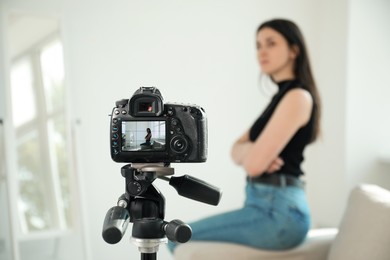 Photo of Woman on sofa in studio, focus on video camera recording her