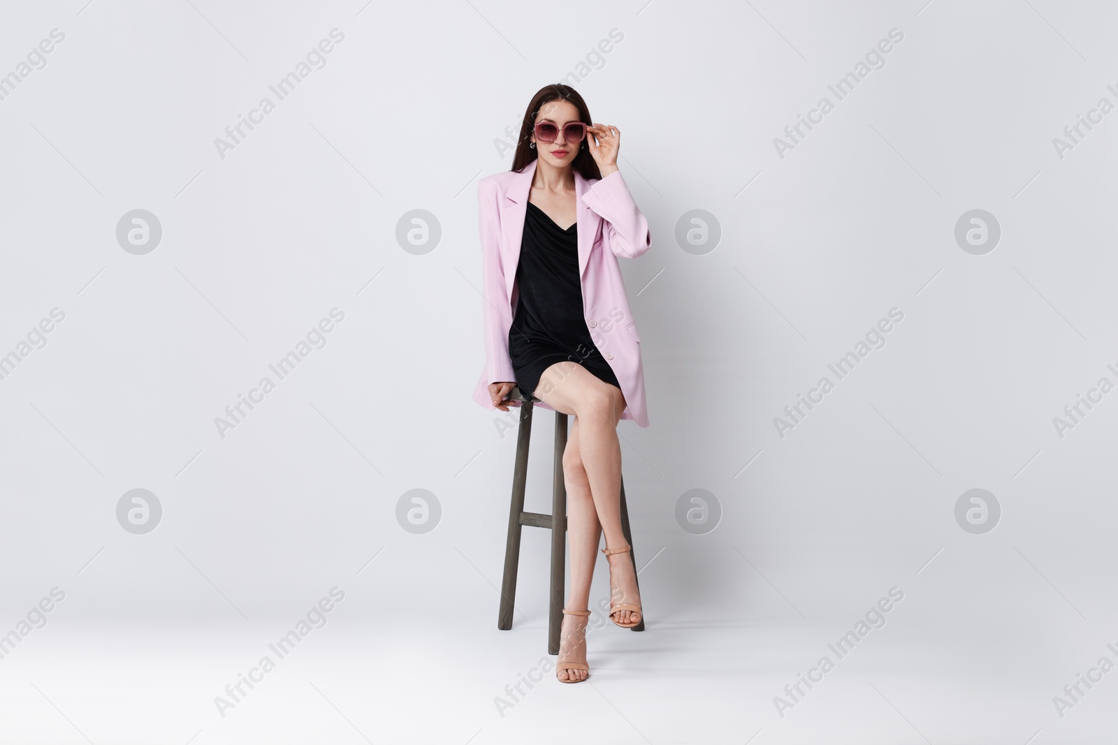 Photo of Beautiful woman in stylish outfit sitting on chair against white background