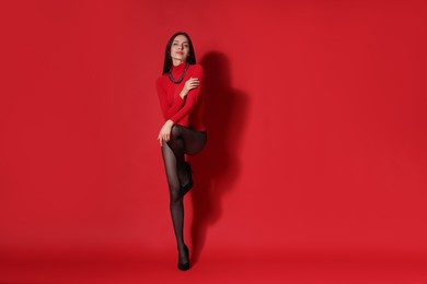 Photo of Full-length portrait of beautiful woman in stylish outfit on red background, space for text