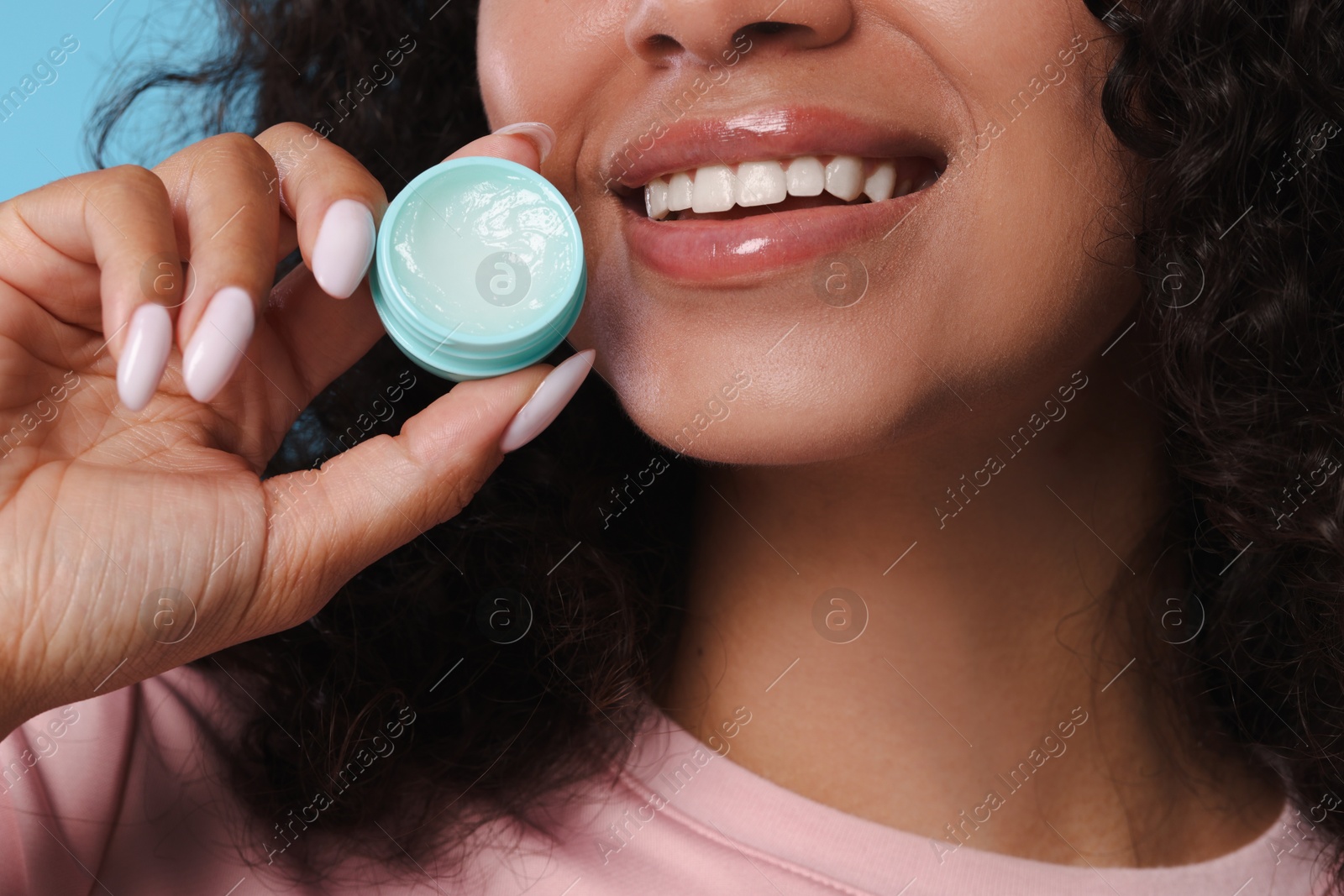Photo of Smiling woman with lip balm on light blue background