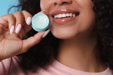 Photo of Smiling woman with lip balm on light blue background