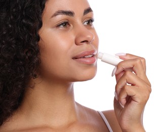 Photo of Beautiful woman applying lip balm onto her lips on white background, closeup