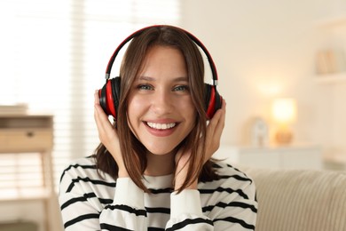 Photo of Portrait of smiling teenage girl in headphones at home