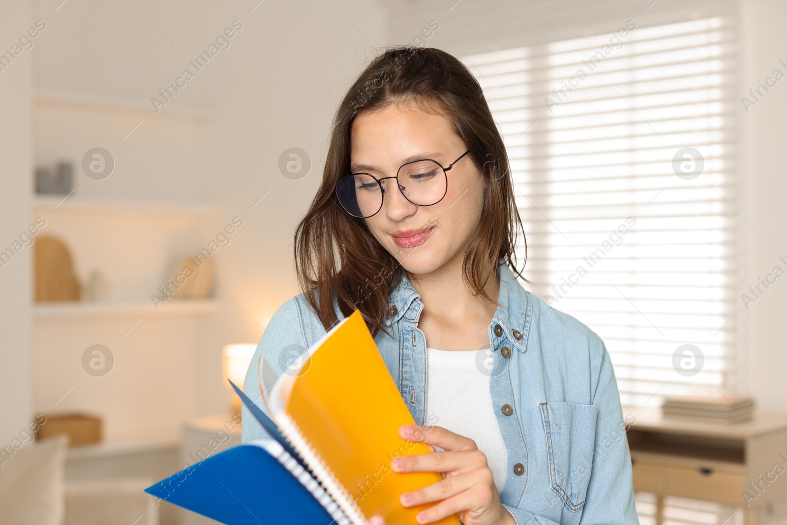 Photo of Beautiful teenage girl with notepads at home