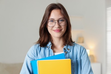 Photo of Portrait of beautiful teenage girl with notepads at home