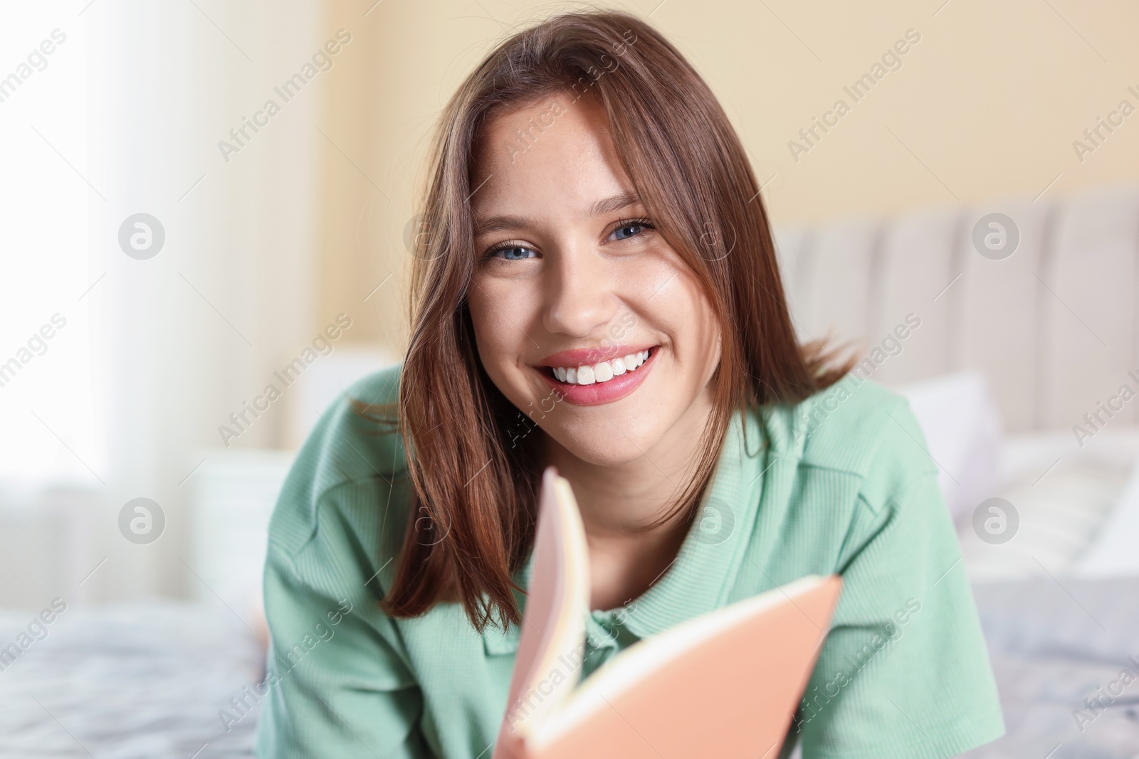 Portrait of smiling teenage girl with book at home Photo of Portrait of smiling teenage girl with book at home
