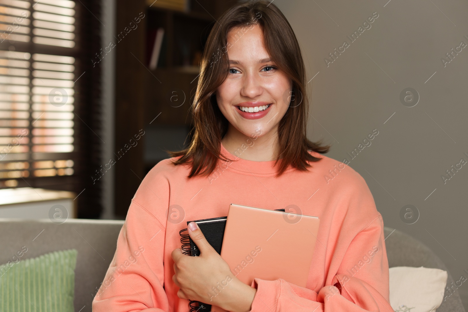 Smiling teenage girl with notebooks at home Photo of Smiling teenage girl with notebooks at home