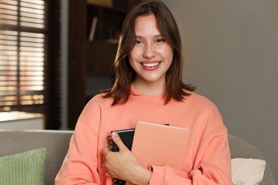Photo of Smiling teenage girl with notebooks at home