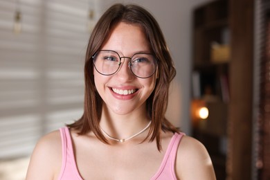 Photo of Portrait of smiling teenage girl in glasses at home