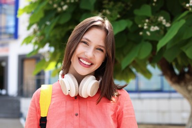 Photo of Portrait of smiling teenage girl with headphones outdoors