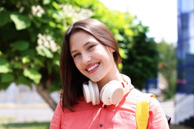 Photo of Portrait of smiling teenage girl with headphones outdoors
