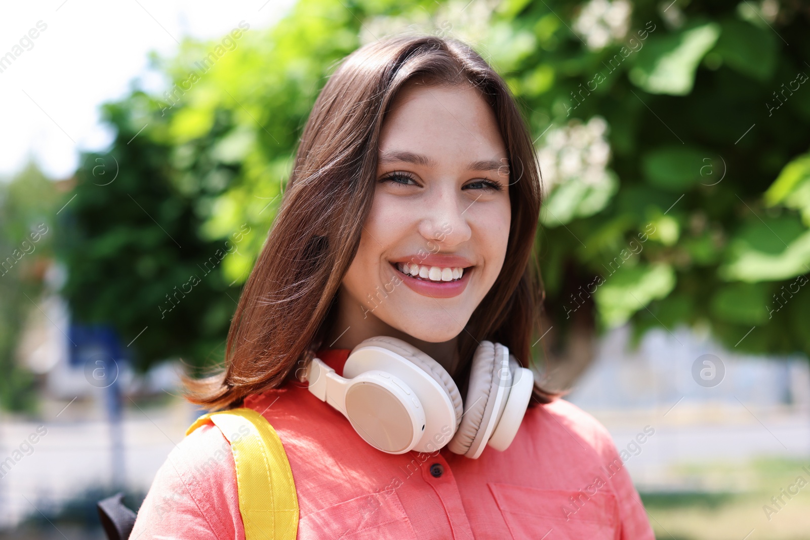 Portrait of smiling teenage girl with headphones outdoors Photo of Portrait of smiling teenage girl with headphones outdoors