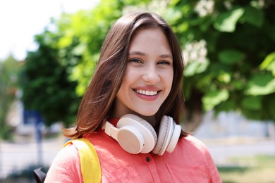 Photo of Portrait of smiling teenage girl with headphones outdoors