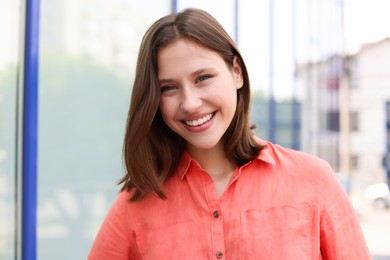 Photo of Portrait of smiling teenage girl near building outdoors
