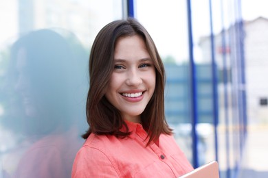 Photo of Portrait of smiling teenage girl near building outdoors