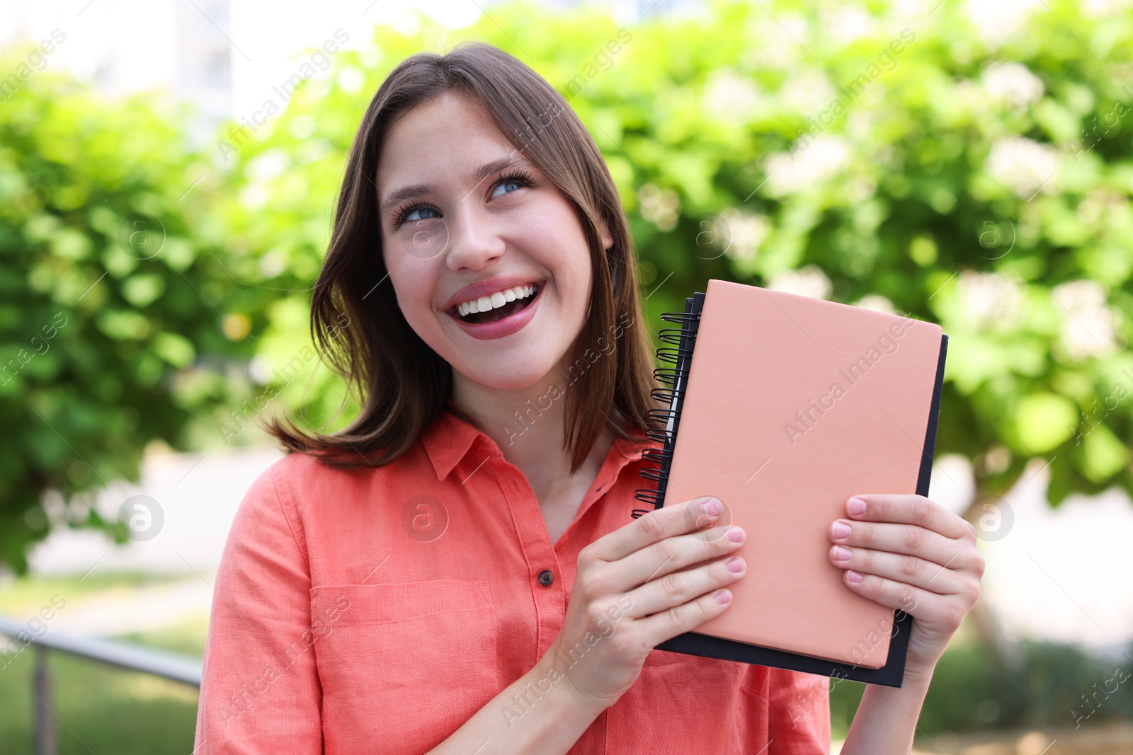 Smiling teenage girl with notepads on city street Photo of Smiling teenage girl with notepads on city street