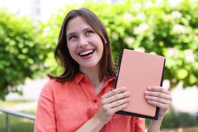 Photo of Smiling teenage girl with notepads on city street