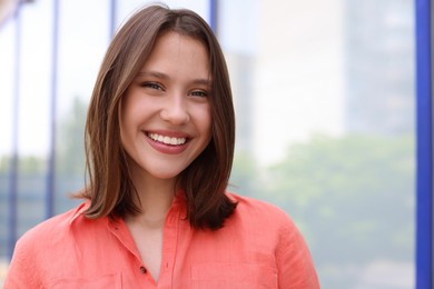 Photo of Portrait of smiling teenage girl near building outdoors