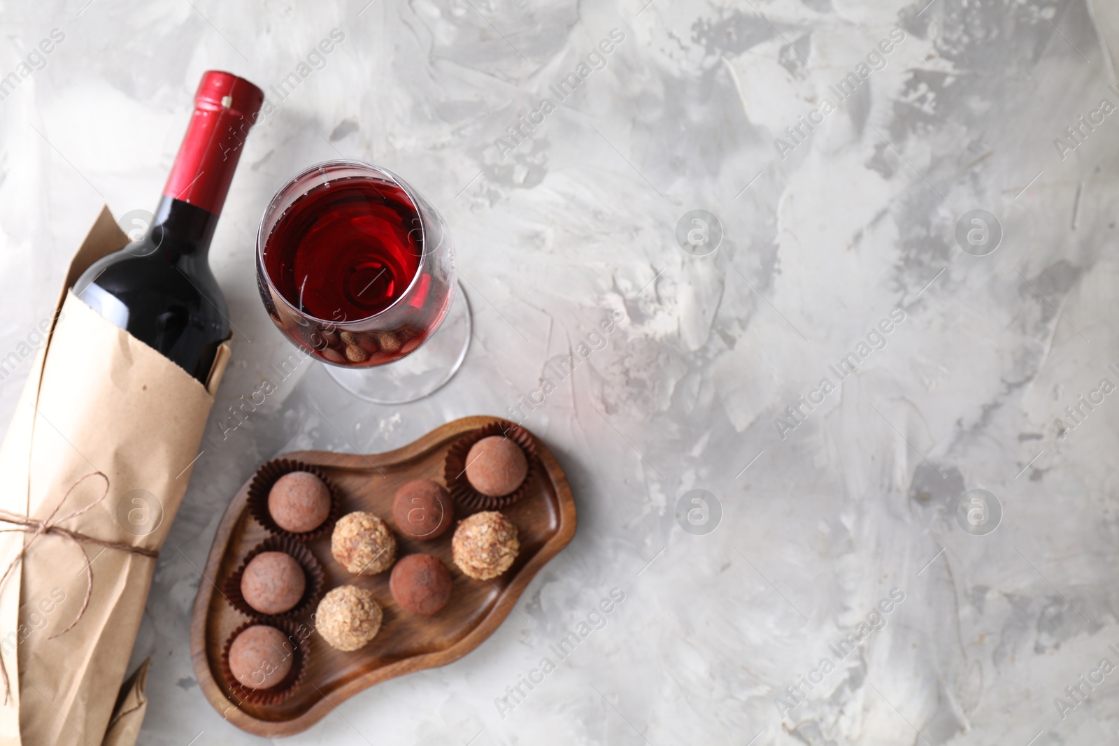 Delicious truffle bonbons and red wine on light grey background, flat lay. Space for text Photo of Delicious truffle bonbons and red wine on light grey background, flat lay. Space for text