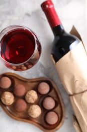 Photo of Delicious truffle bonbons and red wine on light grey background, flat lay