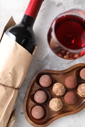 Photo of Delicious truffle bonbons and red wine on light grey background, flat lay