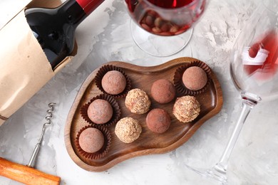 Photo of Delicious truffle bonbons and red wine on light grey background, flat lay