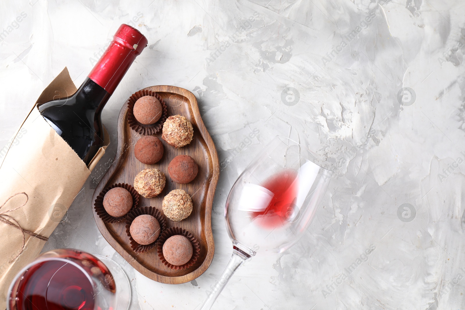Delicious truffle bonbons and red wine on light grey background, flat lay. Space for text Photo of Delicious truffle bonbons and red wine on light grey background, flat lay. Space for text
