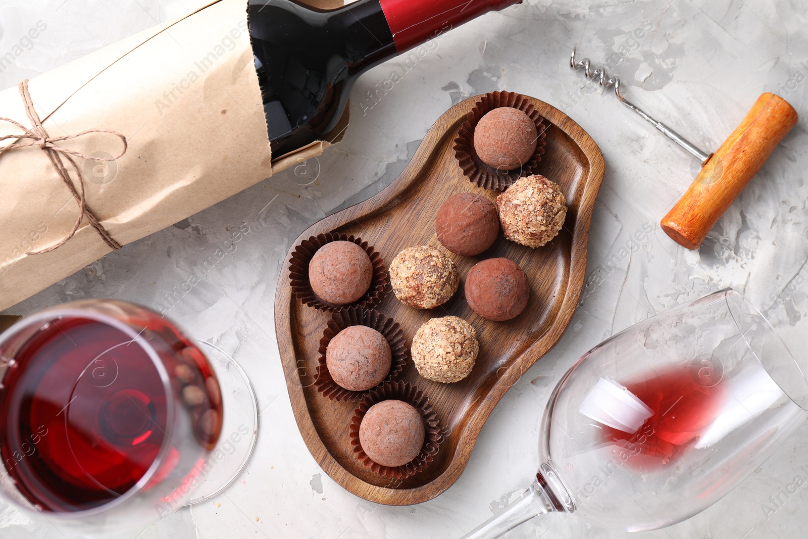 Photo of Delicious truffle bonbons and red wine on light grey background, flat lay