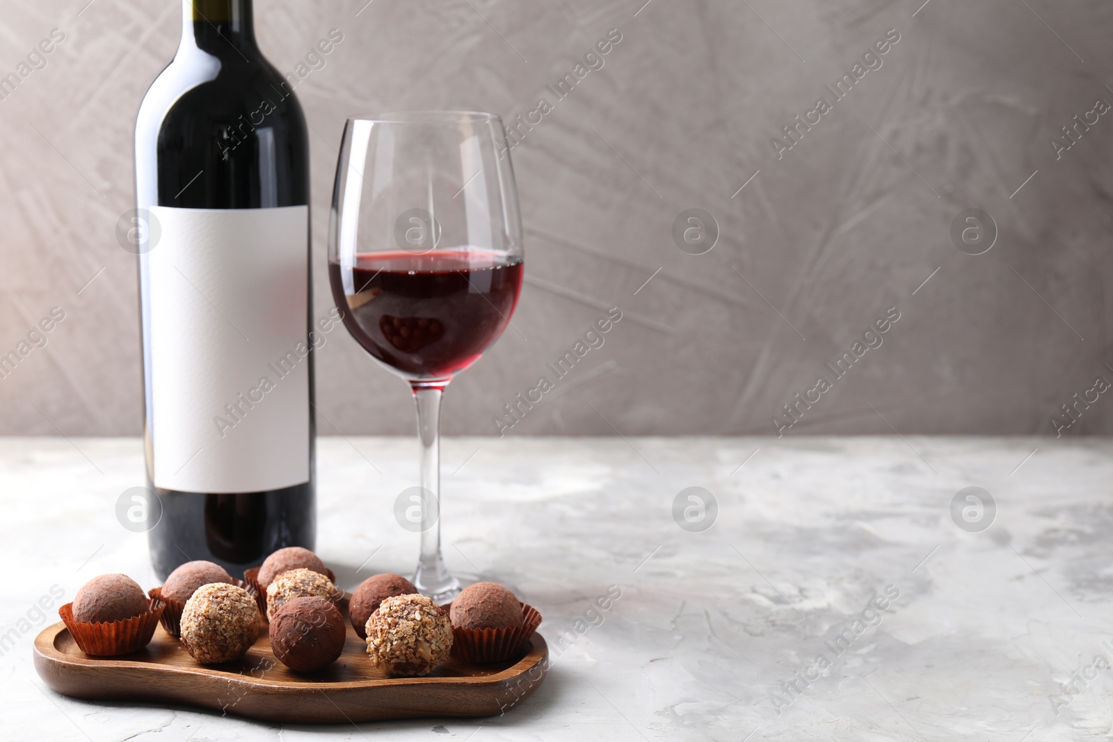 Delicious truffle bonbons and red wine on light grey background. Space for text Photo of Delicious truffle bonbons and red wine on light grey background. Space for text