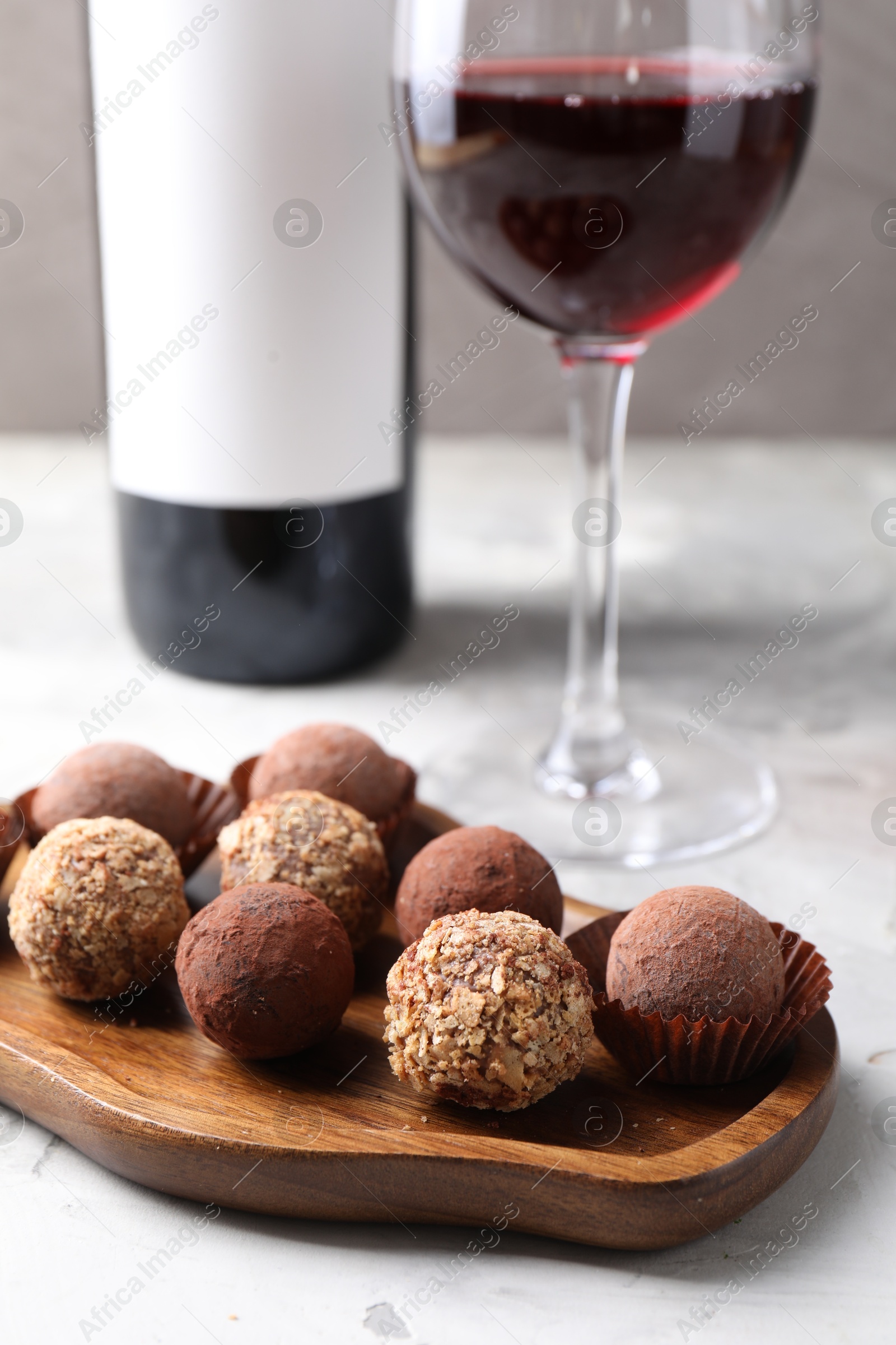 Delicious truffle bonbons and red wine on light grey background, closeup Photo of Delicious truffle bonbons and red wine on light grey background, closeup