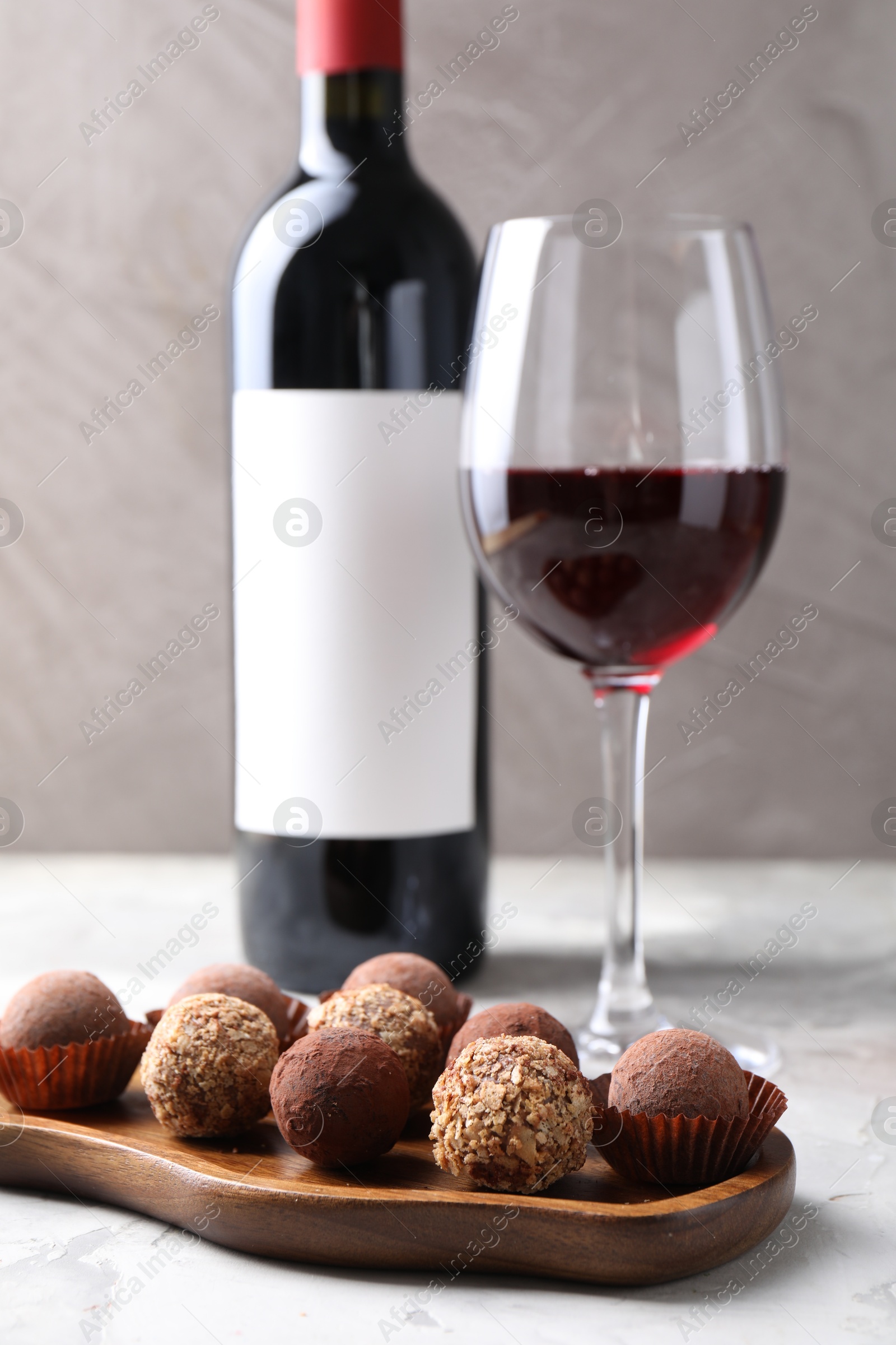 Delicious truffle bonbons and red wine on light grey background, closeup Photo of Delicious truffle bonbons and red wine on light grey background, closeup