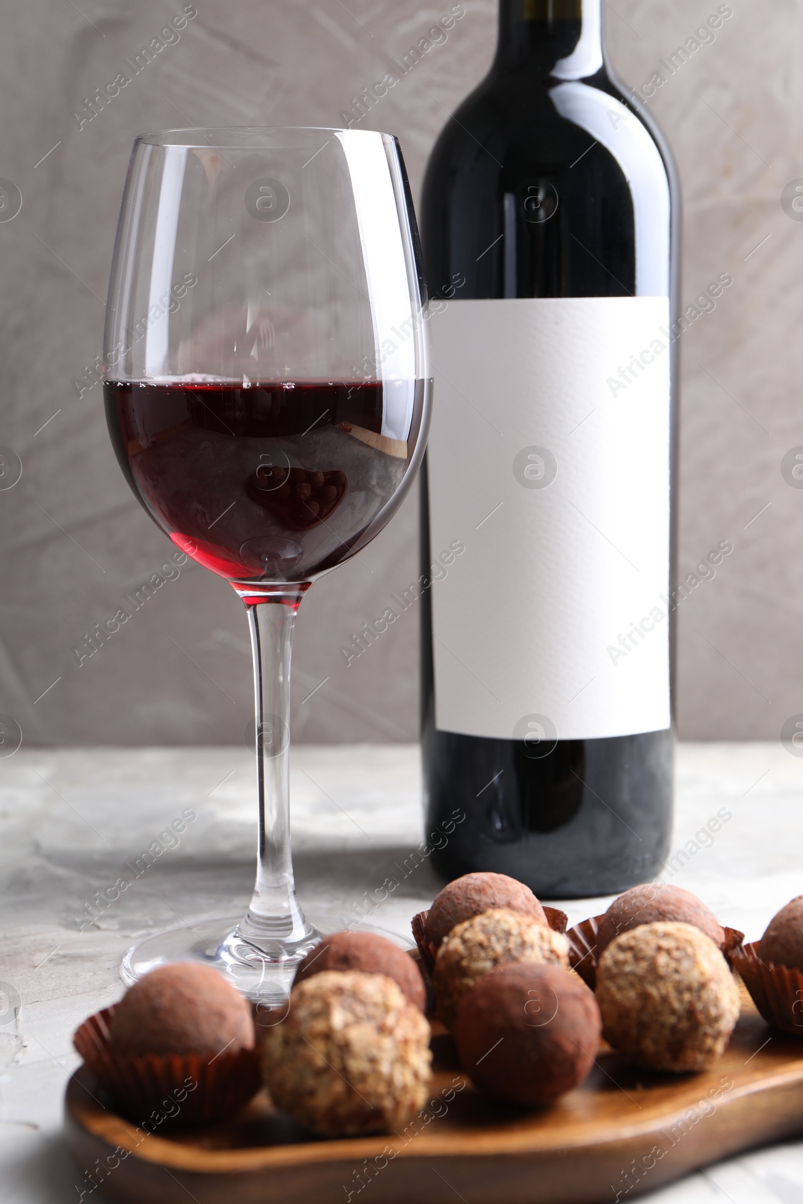 Delicious truffle bonbons and red wine on light grey background, closeup Photo of Delicious truffle bonbons and red wine on light grey background, closeup