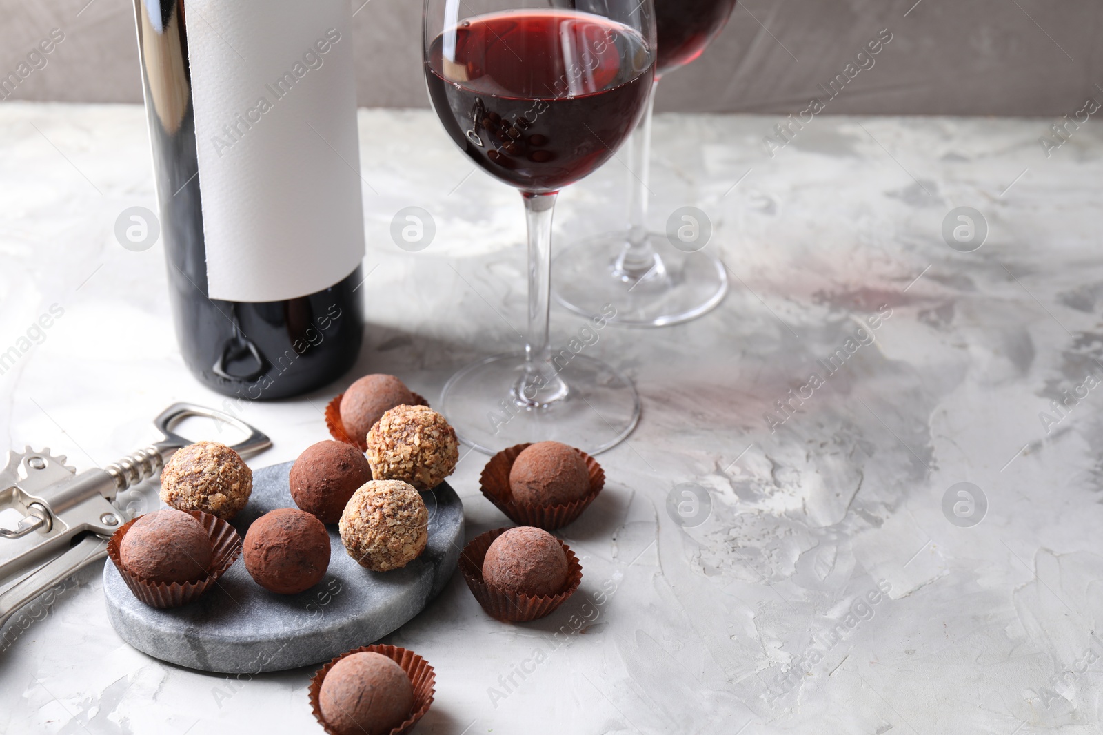 Delicious truffle bonbons and red wine on light grey background. Space for text Photo of Delicious truffle bonbons and red wine on light grey background. Space for text