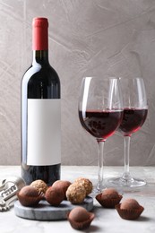 Photo of Delicious truffle bonbons and red wine on light grey background
