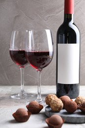 Photo of Delicious truffle bonbons and red wine on light grey background