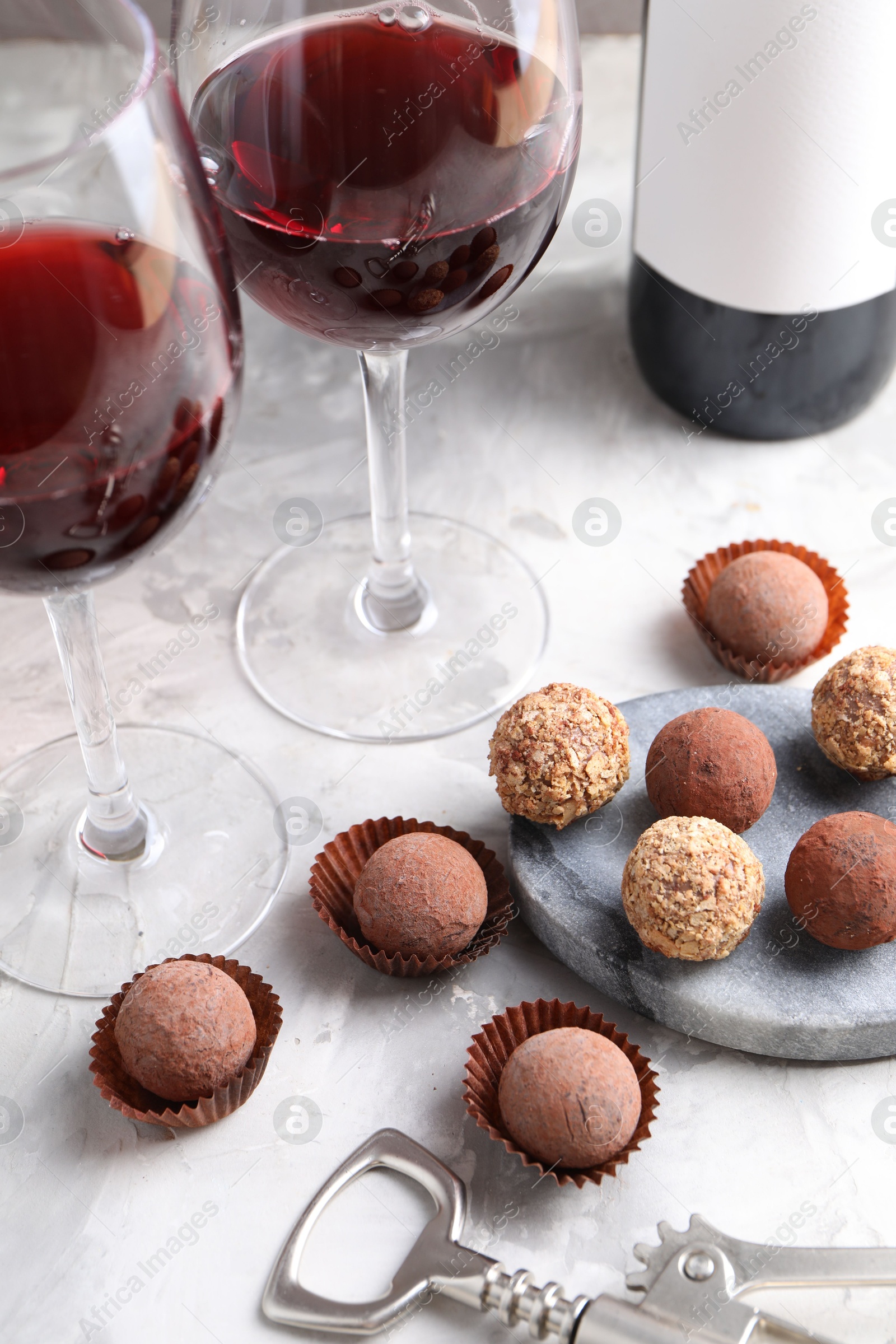 Delicious truffle bonbons and red wine on light grey background, closeup Photo of Delicious truffle bonbons and red wine on light grey background, closeup