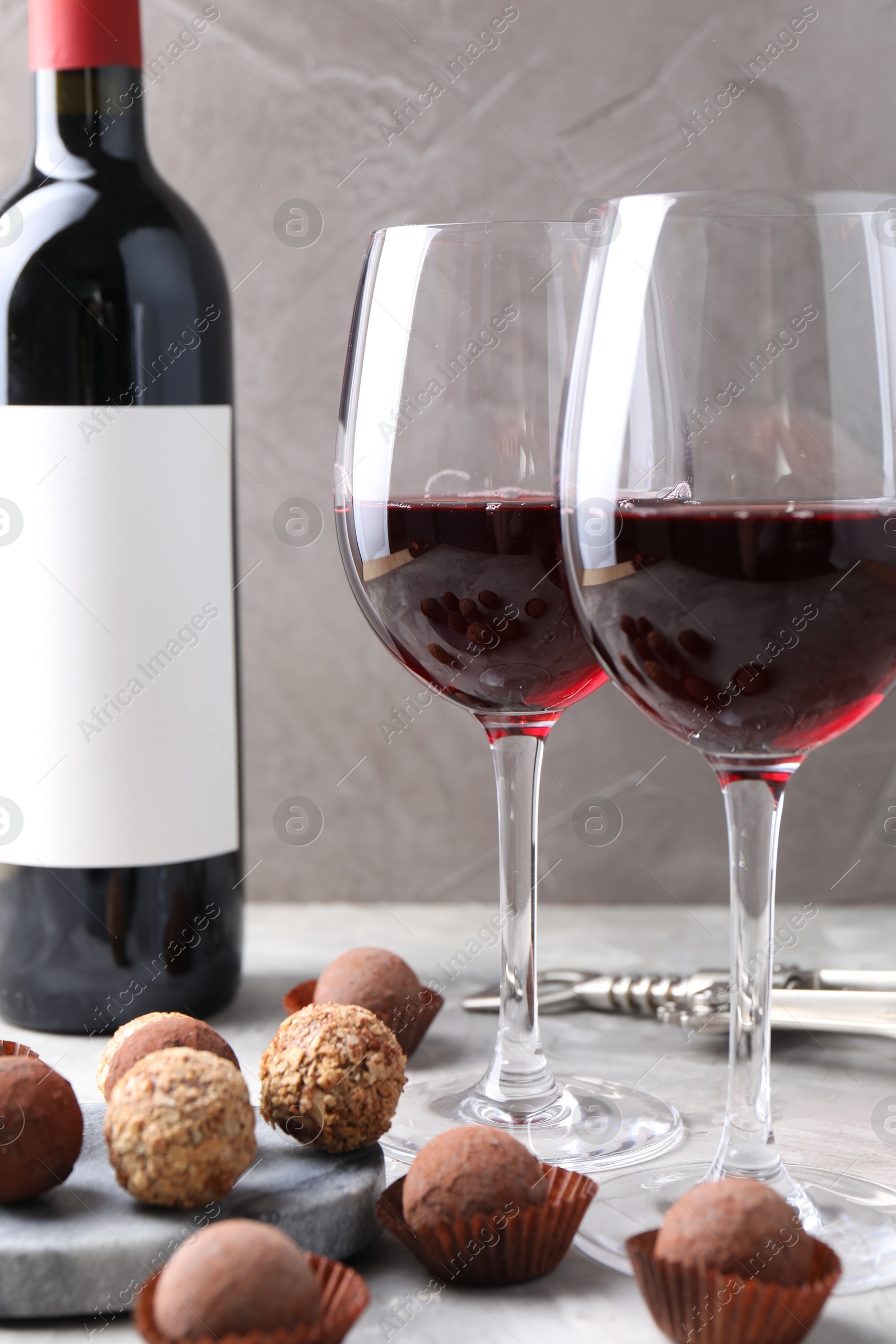 Delicious truffle bonbons and red wine on light grey background, closeup Photo of Delicious truffle bonbons and red wine on light grey background, closeup