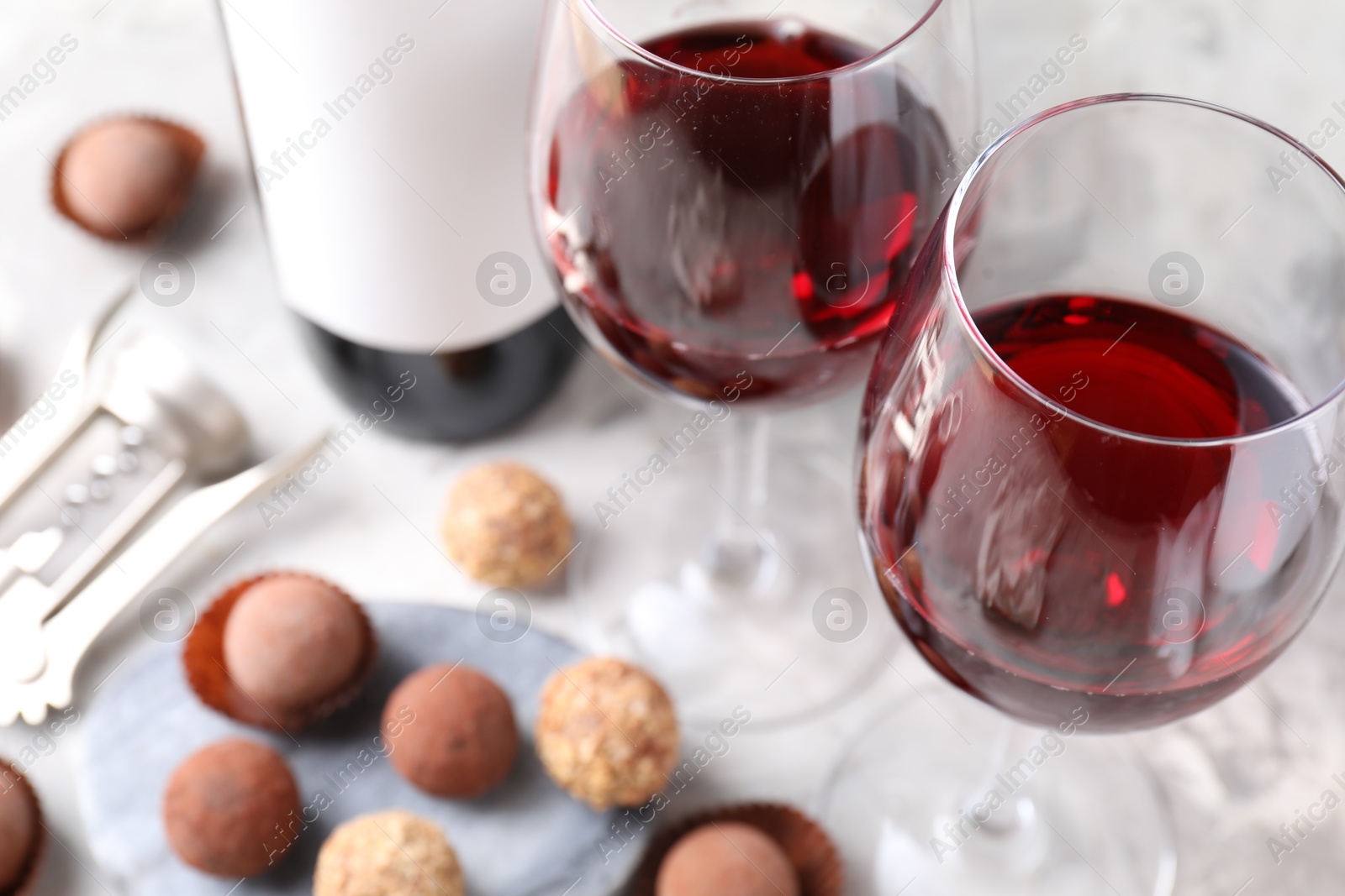 Delicious truffle bonbons and red wine on light grey background, closeup Photo of Delicious truffle bonbons and red wine on light grey background, closeup