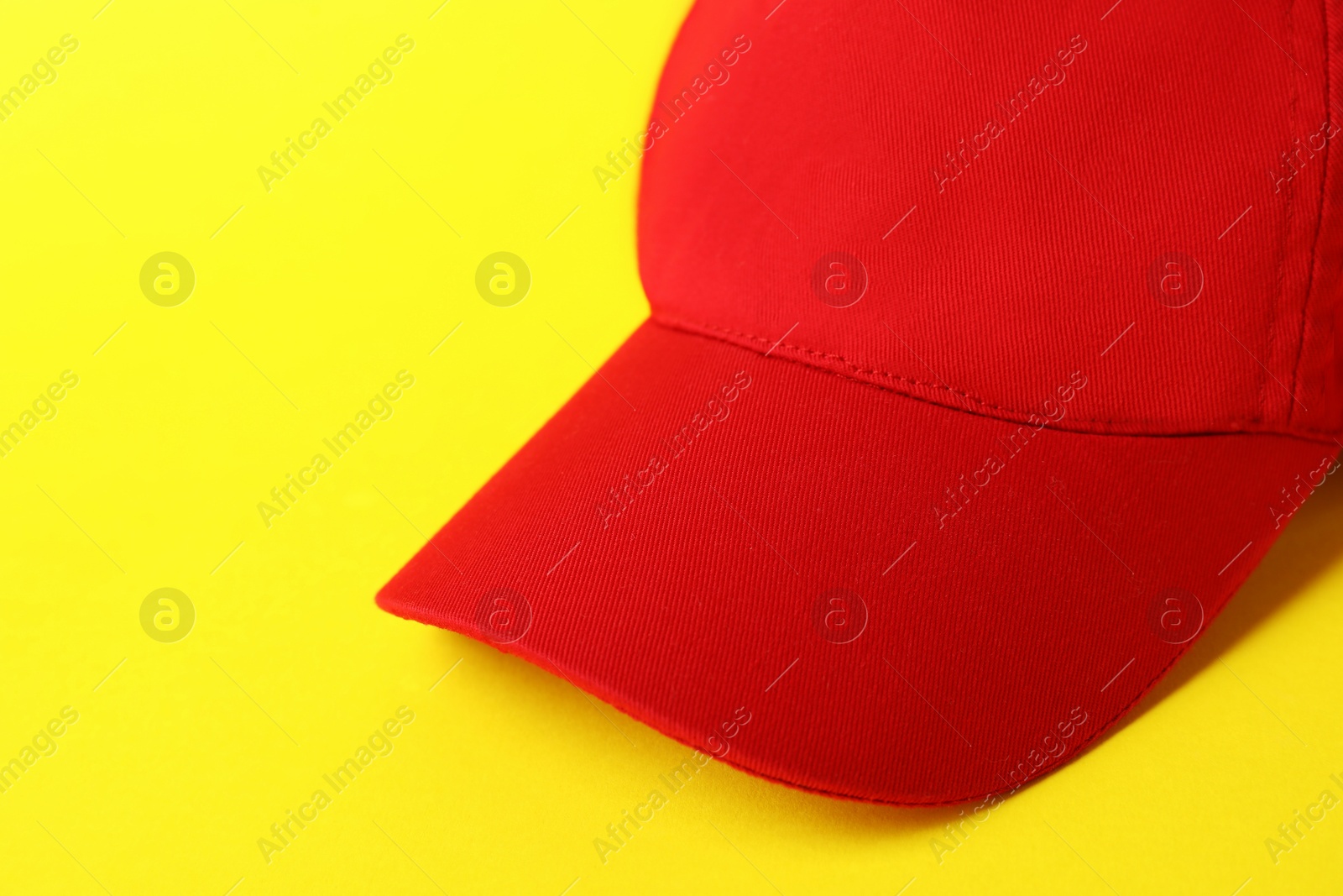 Red baseball hat on yellow background, closeup. Space for text Photo of Red baseball hat on yellow background, closeup. Space for text