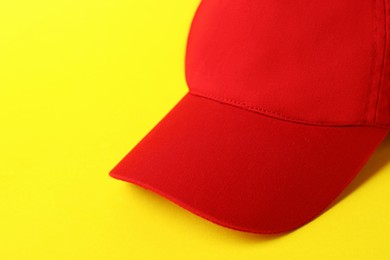 Photo of Red baseball hat on yellow background, closeup. Space for text