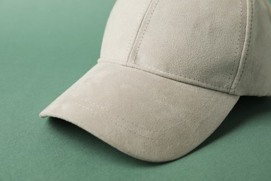Photo of Beige baseball hat on green background, closeup. Mockup for design