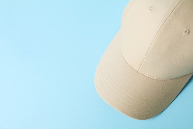 Photo of Beige baseball hat on light blue background, top view. Space for text
