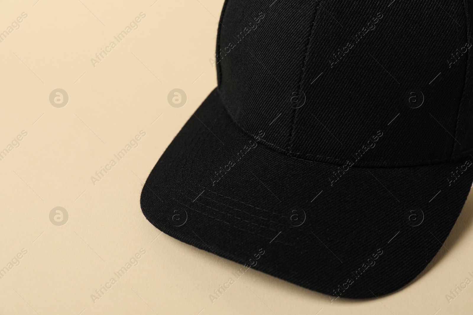 Photo of Black baseball hat on beige background, closeup. Space for text