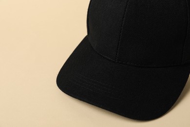 Photo of Black baseball hat on beige background, closeup. Space for text