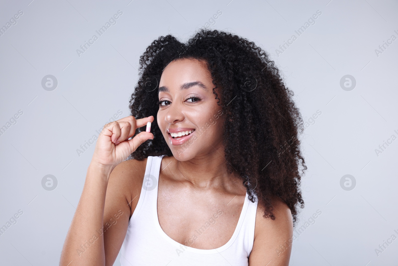 Photo of Beautiful Brazilian woman with collagen pill on gray background