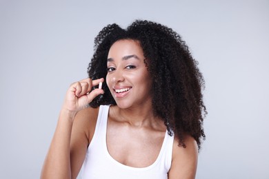 Photo of Beautiful Brazilian woman with collagen pill on gray background